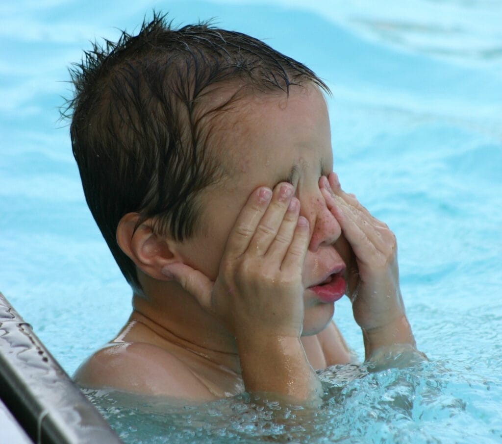 Boy at pool scratching his eyes
