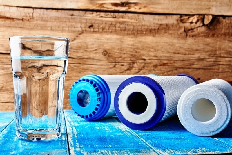 Carbon cartridges and a glass of water on a wooden background_ivan_kislitsin_shutterstock