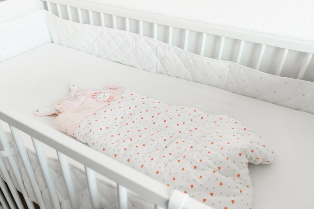 White baby bed with sleeping bag