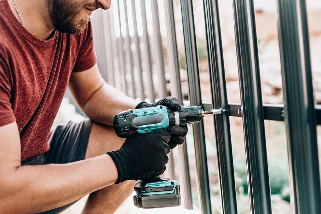 Man Drilling Metal Fence Bogdanhoda Shutterstock 1024x683 