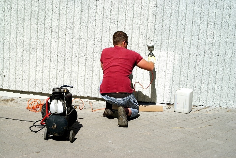 man using paint sprayer and air compressor