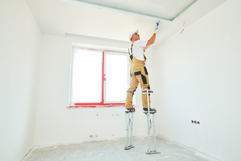 Painter,In,Stilts,With,Putty,Knife.,Plasterer,Smoothing,Ceiling,Surface
