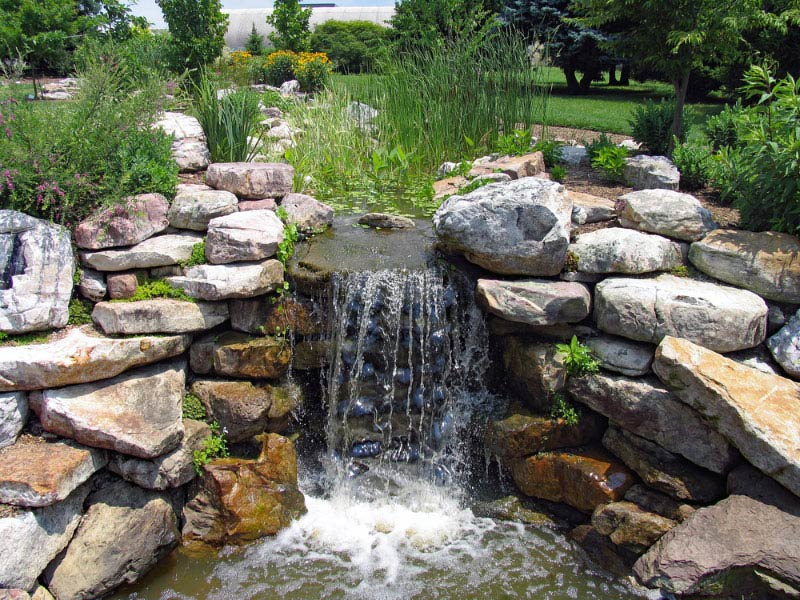 lush green garden with waterfall cascading down the rocky stones