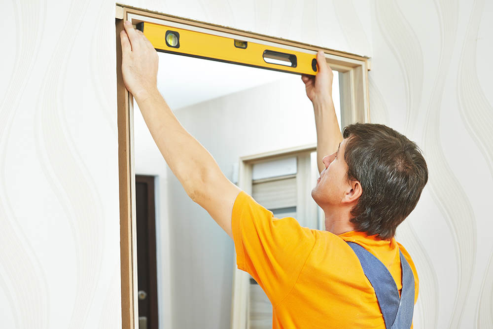Male carpenter leveling door frame