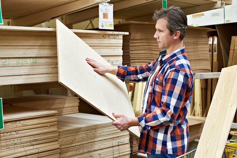 man chooses and buys plywood in a construction supermarket