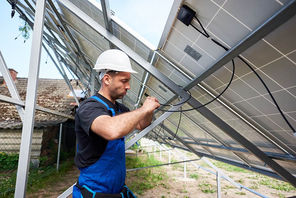 man connecting junction box to the solar panels