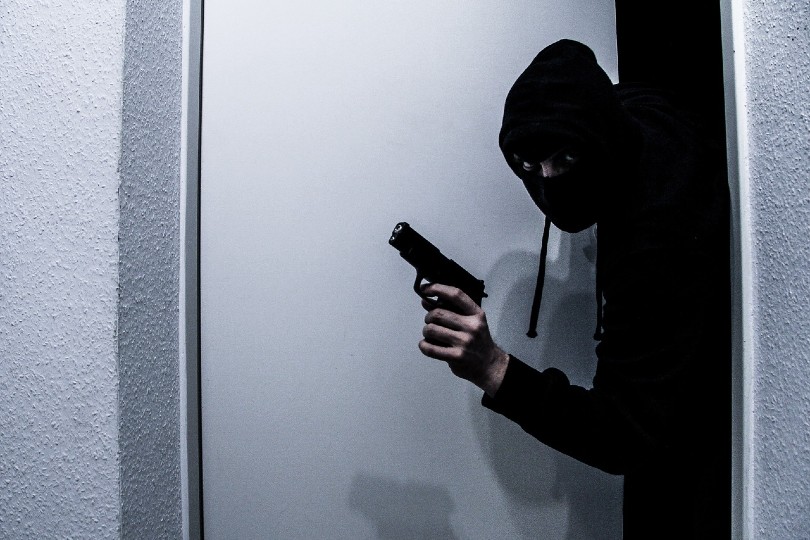 masked thief breaking in a home