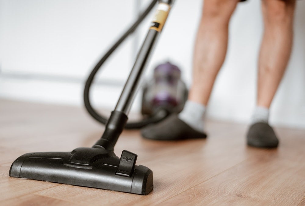 person vacuuming a wood floor