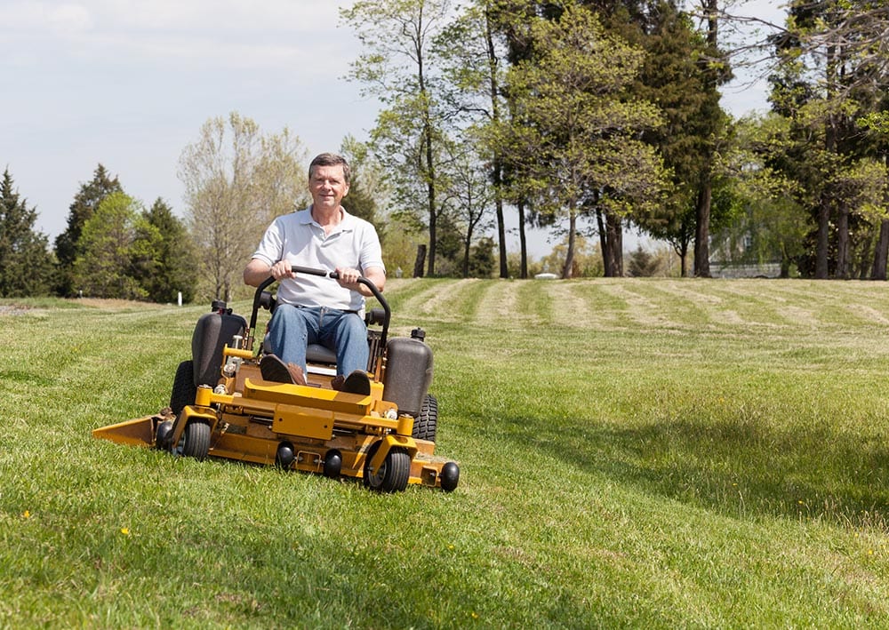 man cutting grass using zero turn mower