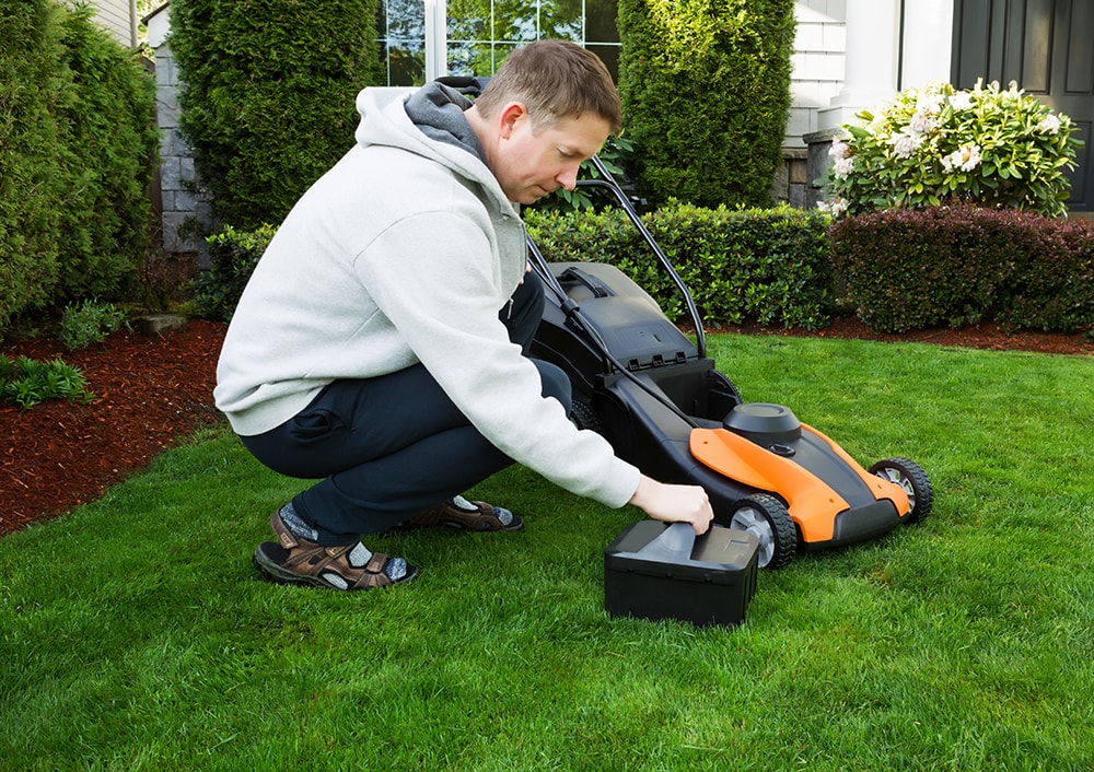Man putting battery on lawn mower