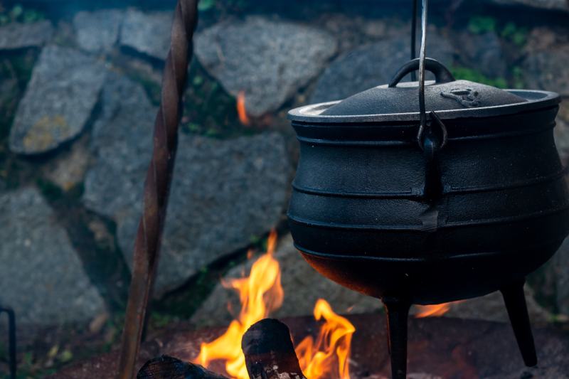 field kitchen with metal cauldron on fire while cooking hot soup