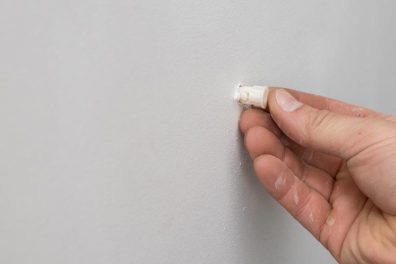hand poking on drywall anchor