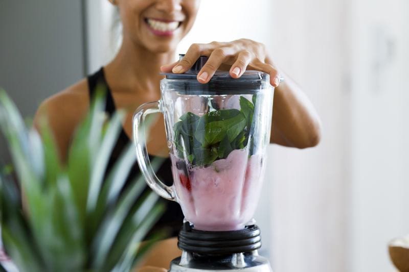 Woman using blender making a smoothie