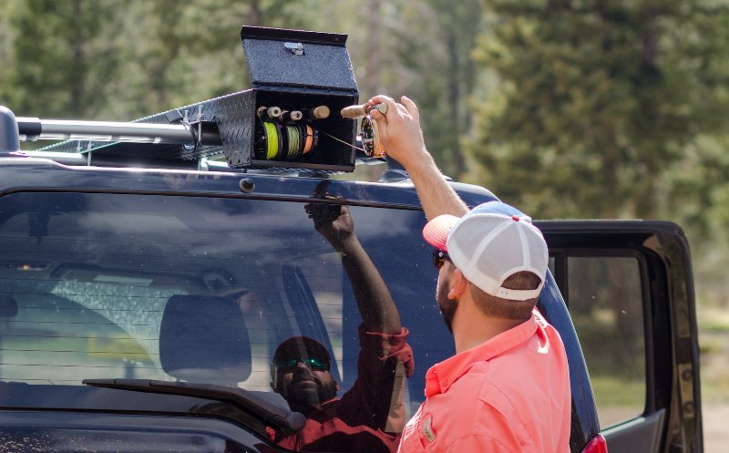 man standing beside their car storing their fishing rods on top