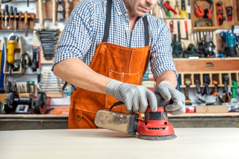 man using an orbital sander in his woodwork