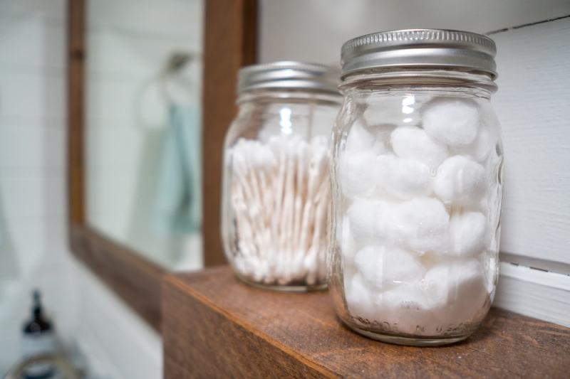 Cotton balls and cotton swabs in mason jars on a bathroom shelf