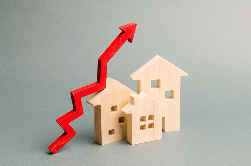 Miniature wooden houses and red arrow up Increase