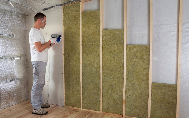 man working on exposed wall with insulation