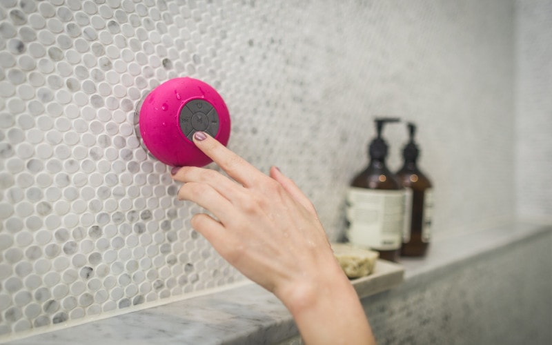 person pressing button on waterproof bluetooth speaker