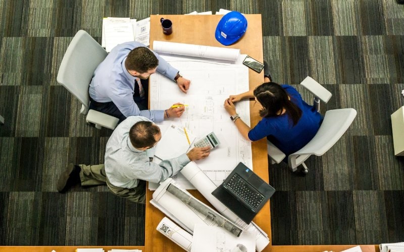 two men and a woman consulting over construction plans