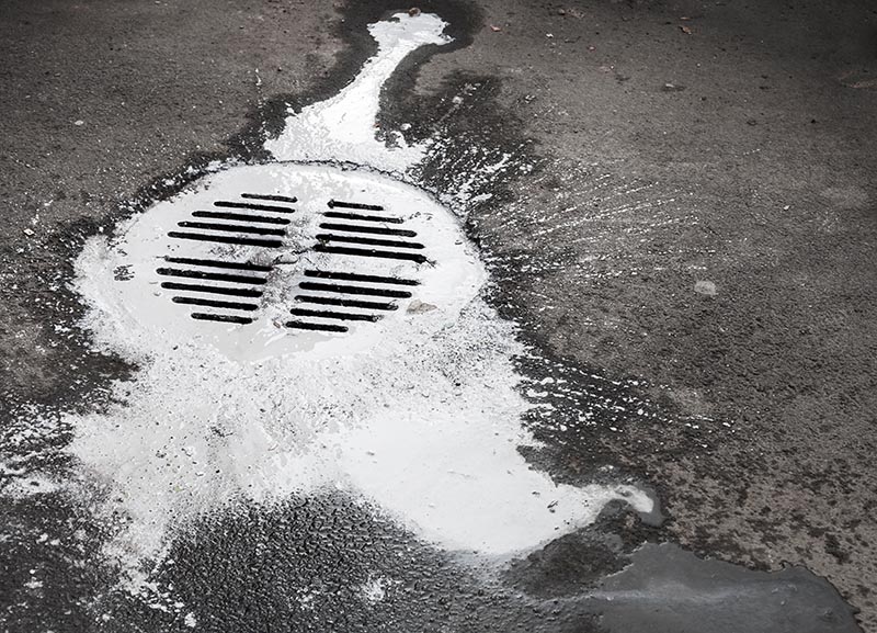 White paint flows into the manhole