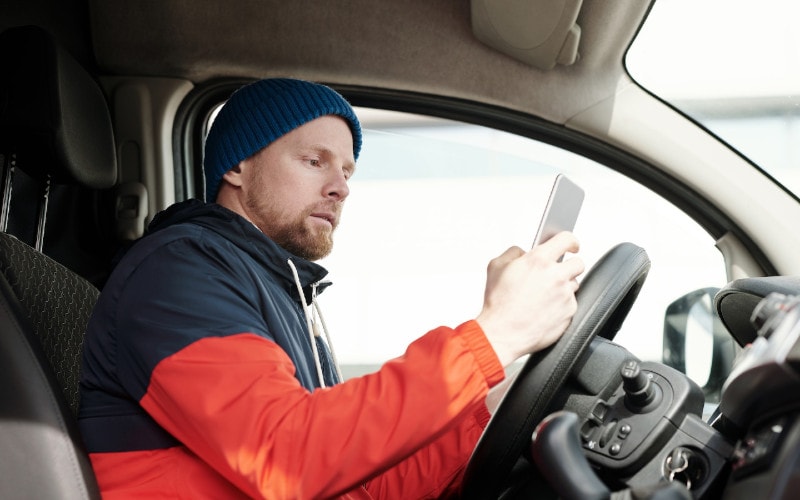 bearded man using their phone inside the car