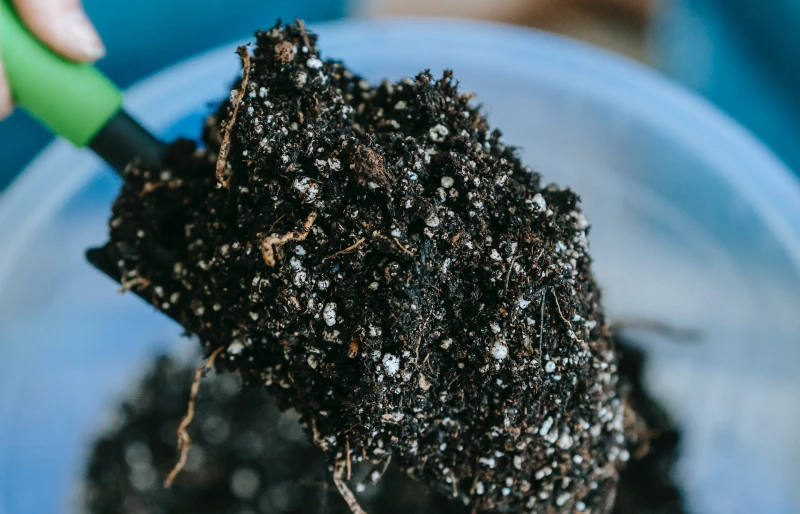 gardener mixing potting soil with trowel