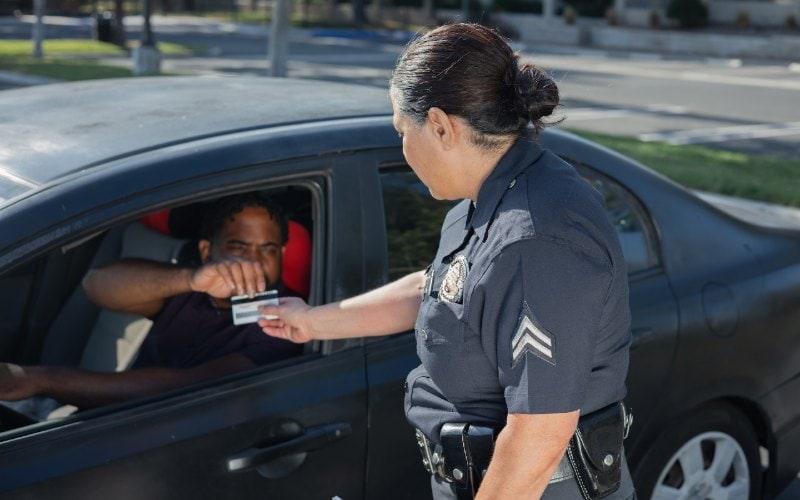 man handing over his license after being pulled over by police