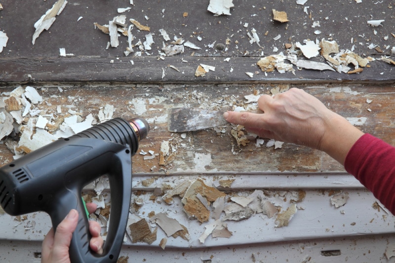 man using heat gun on wooden floor