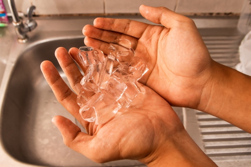 mans hand holding ice tubes