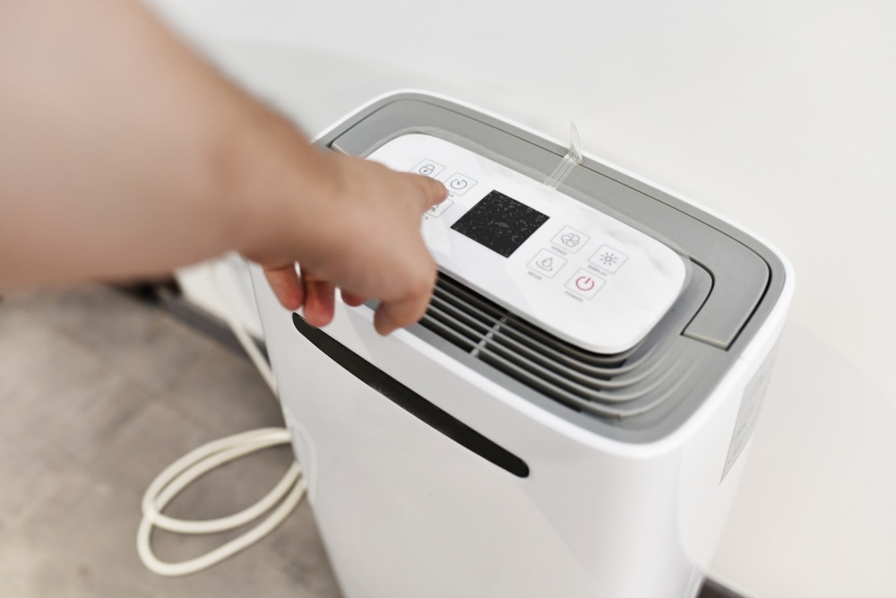 man's hand turning on a dehumidifier