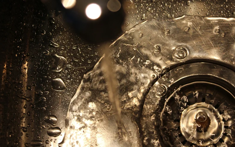 water pouring from faucet into sink drain