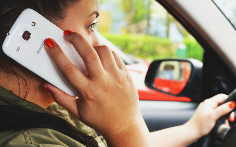 woman taking a call on her phone while driving her car
