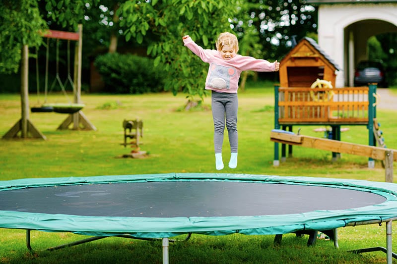 Little preschool girl jumping on trampoline