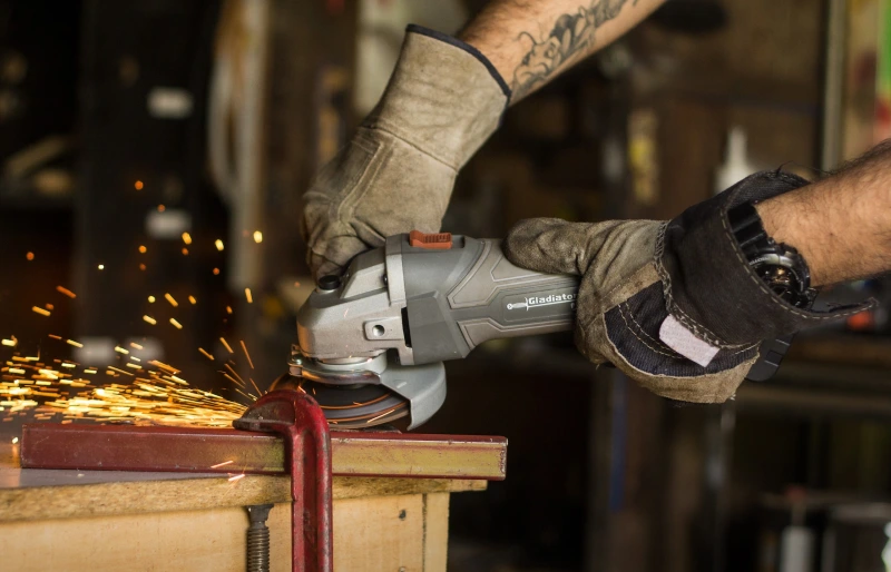 person wearing work gloves using an angle grinder