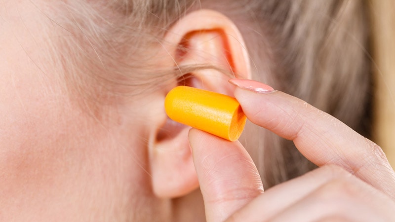 woman putting ear plug into her ear