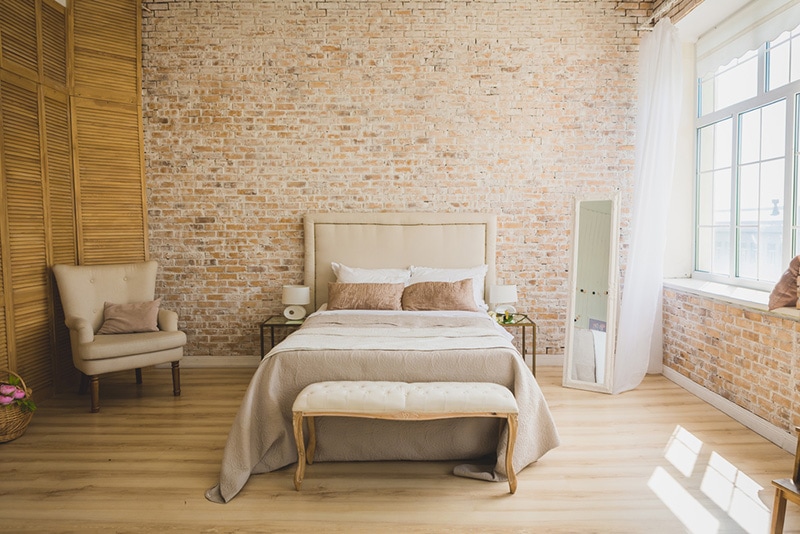 Beautiful loft bedroom with bed near brick wall