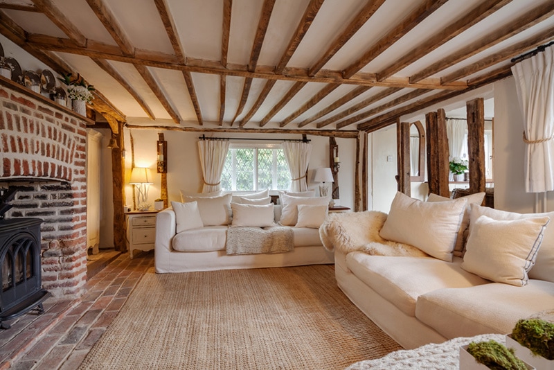 Century English cottage living room with cast iron fire beutifully decorated in pastel colours and furnishings with expose brick floor