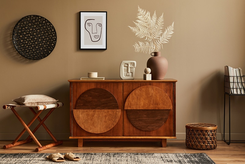 Stylish interior with design wooden commode, stool, dried flowers in vase