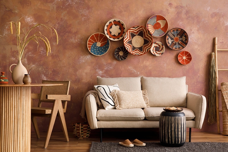 The stylish boho compostion at living room interior with design beige sofa
