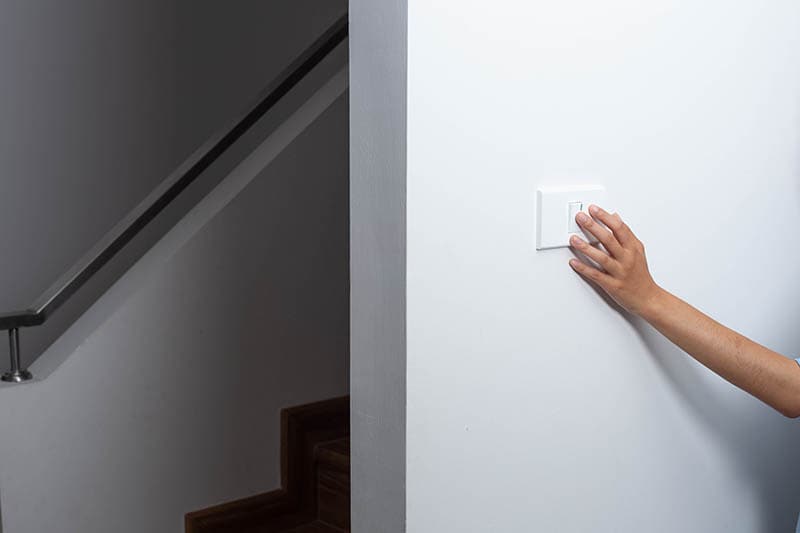 An energy-saving notion is demonstrated by a woman turning out the lights on the sidewalk up the stairs
