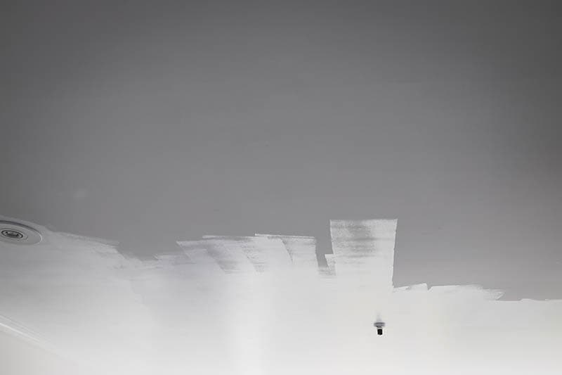 fresh coat of semigloss white paint being rolled on the ceiling