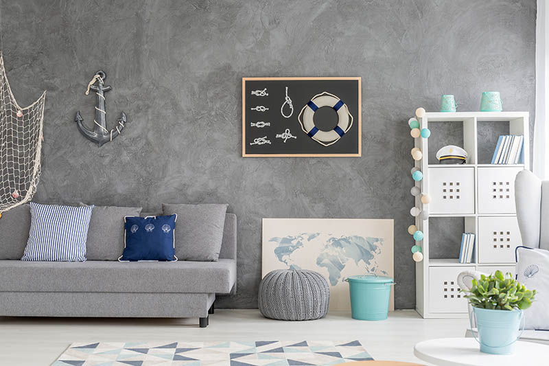 Grey home interior with nautical wall decor, sofa, carpet and white storage unit